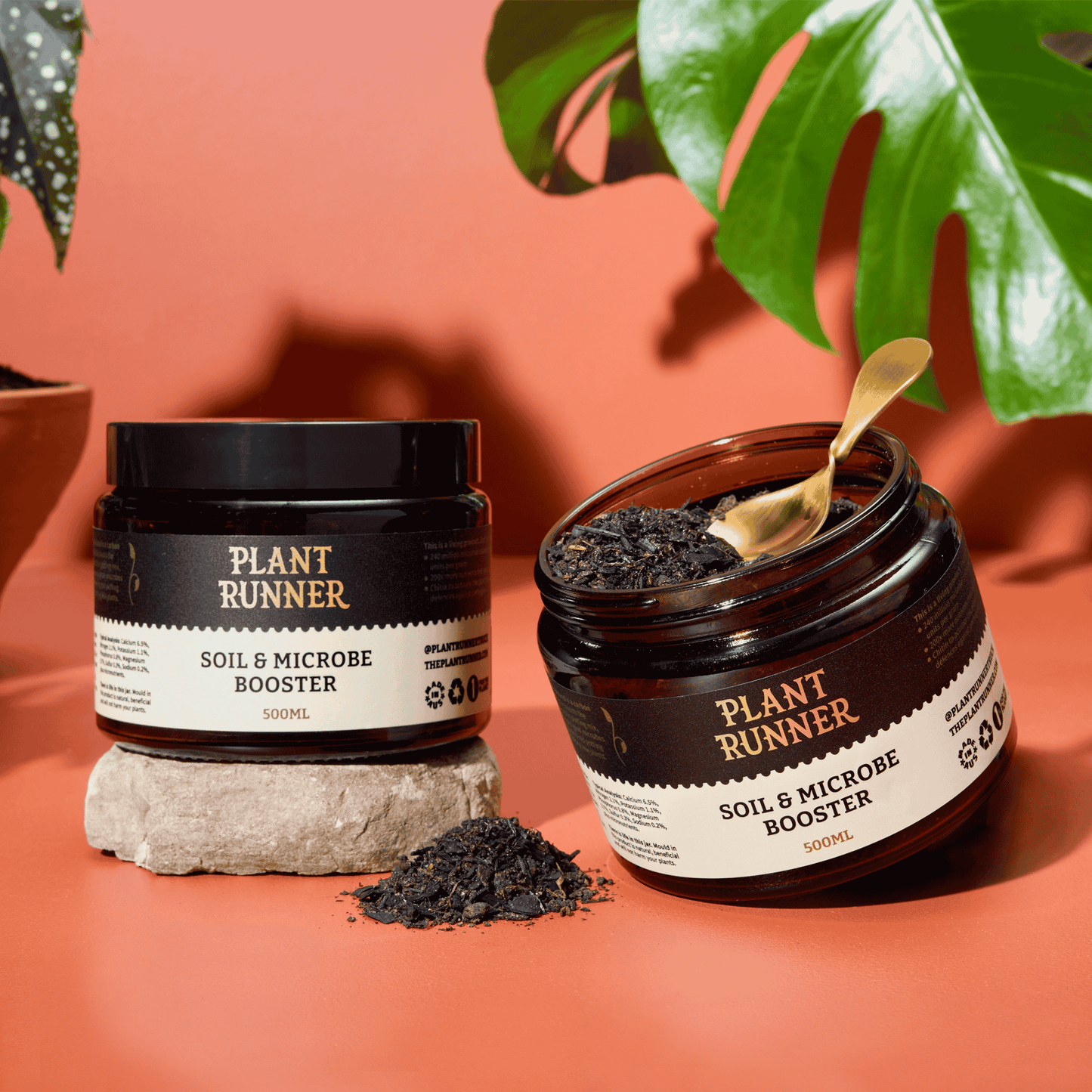 Two jars of 'Plant Runner' soil and microbe booster on a peach background with green leaves.
