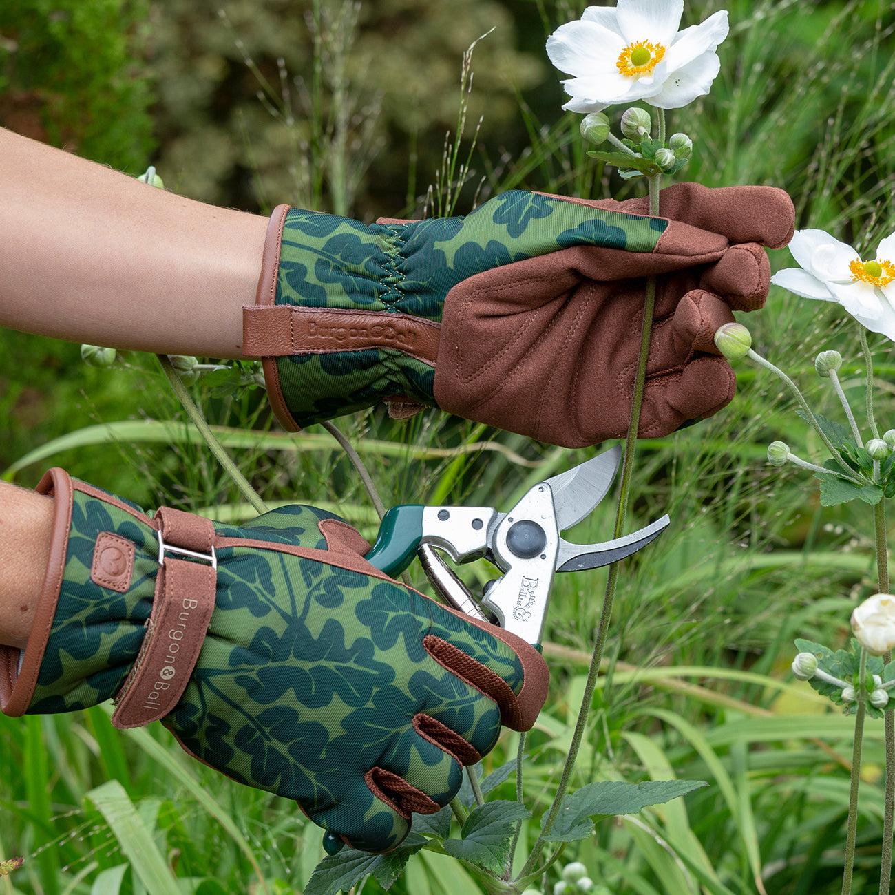 Gardener wearing Burgon & Ball 'Oak Leaf Moss' patterned women's gardening gloves.