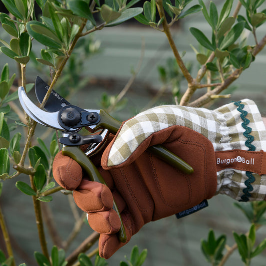 Gardener wearing gingham check gardening gloves in olive green.