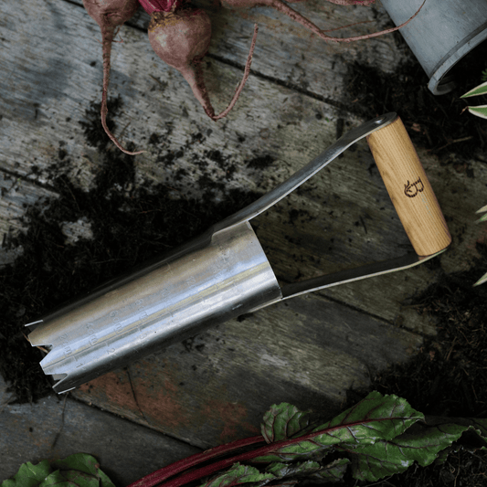 Large bulb planter with wooden handle on a wooden surface with vegetables.