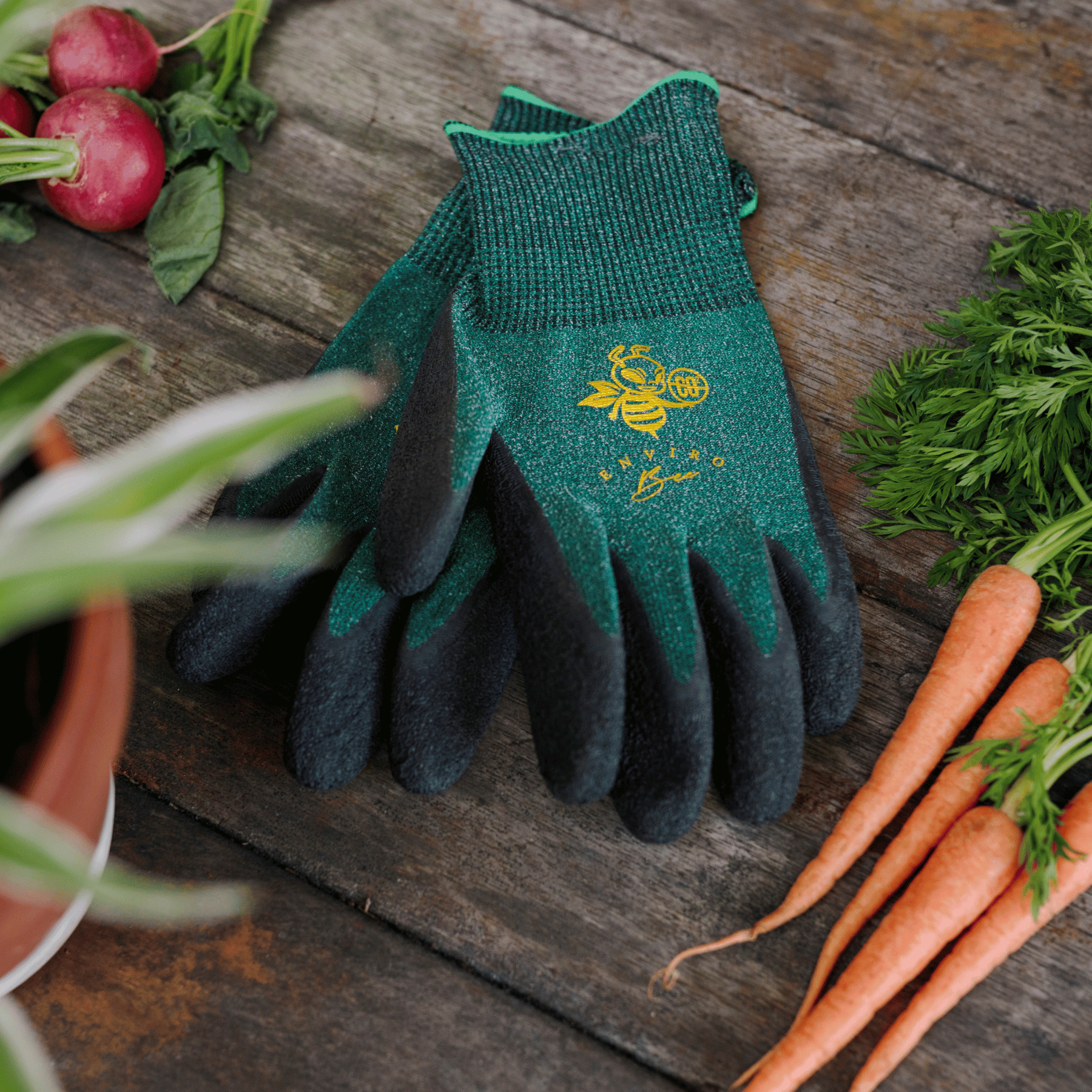 Keepers Enviro Bee Eco Gardening Gloves on potting bench with carrots.