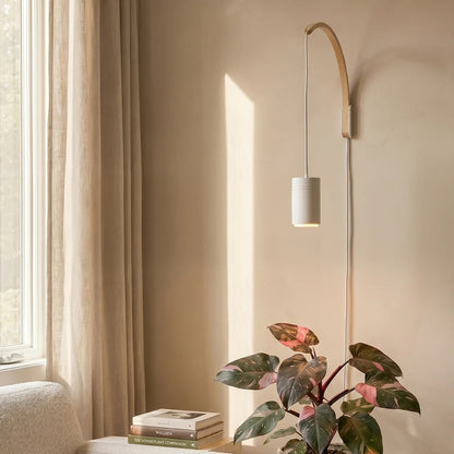 Soltech Luna natural wooden wall arm holding a pendant grow light suspended above a potted indoor houseplant.