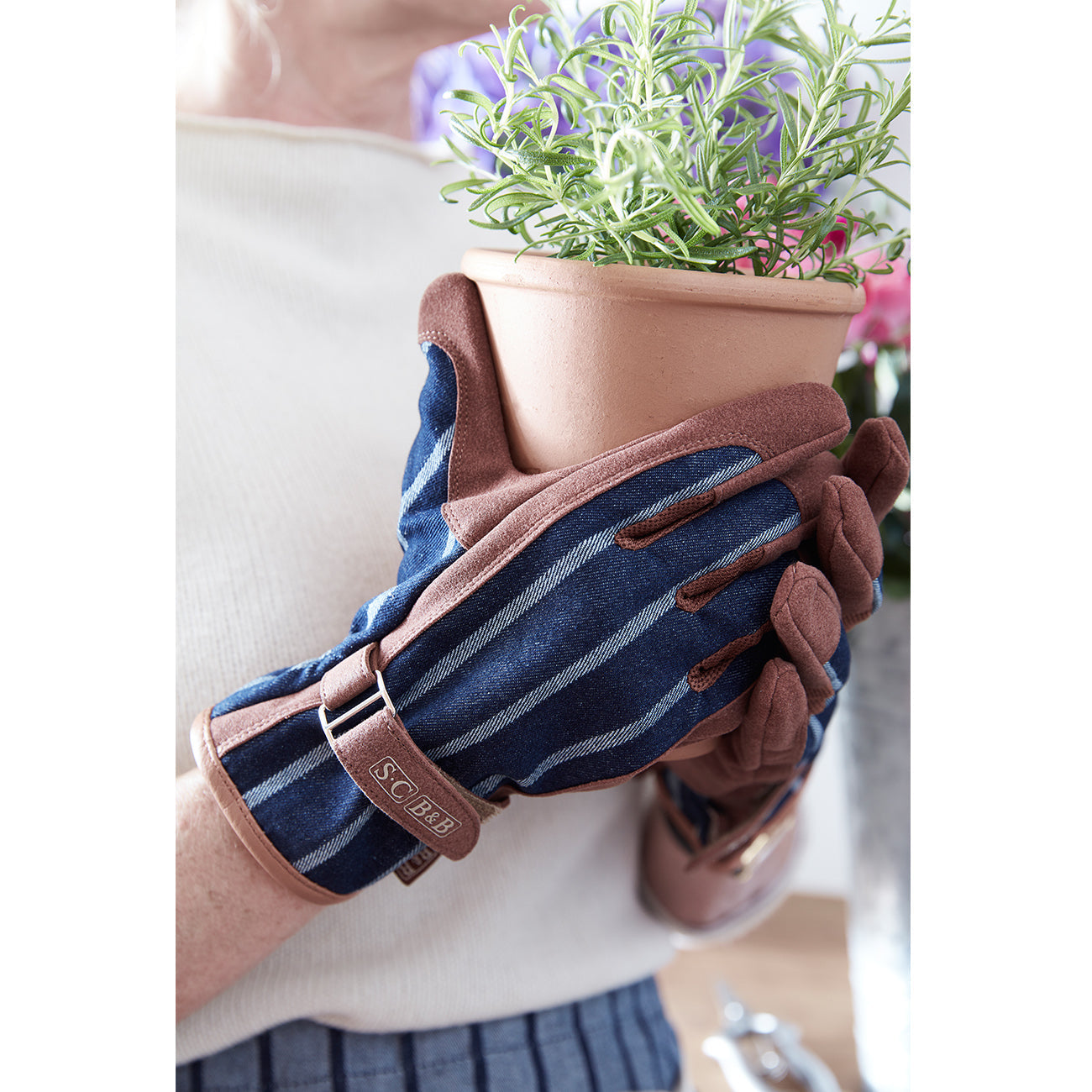 Gardener wearing Sophie Conran for Burgon & Ball Everyday Gardening Gloves in classic blue ticking stripe.