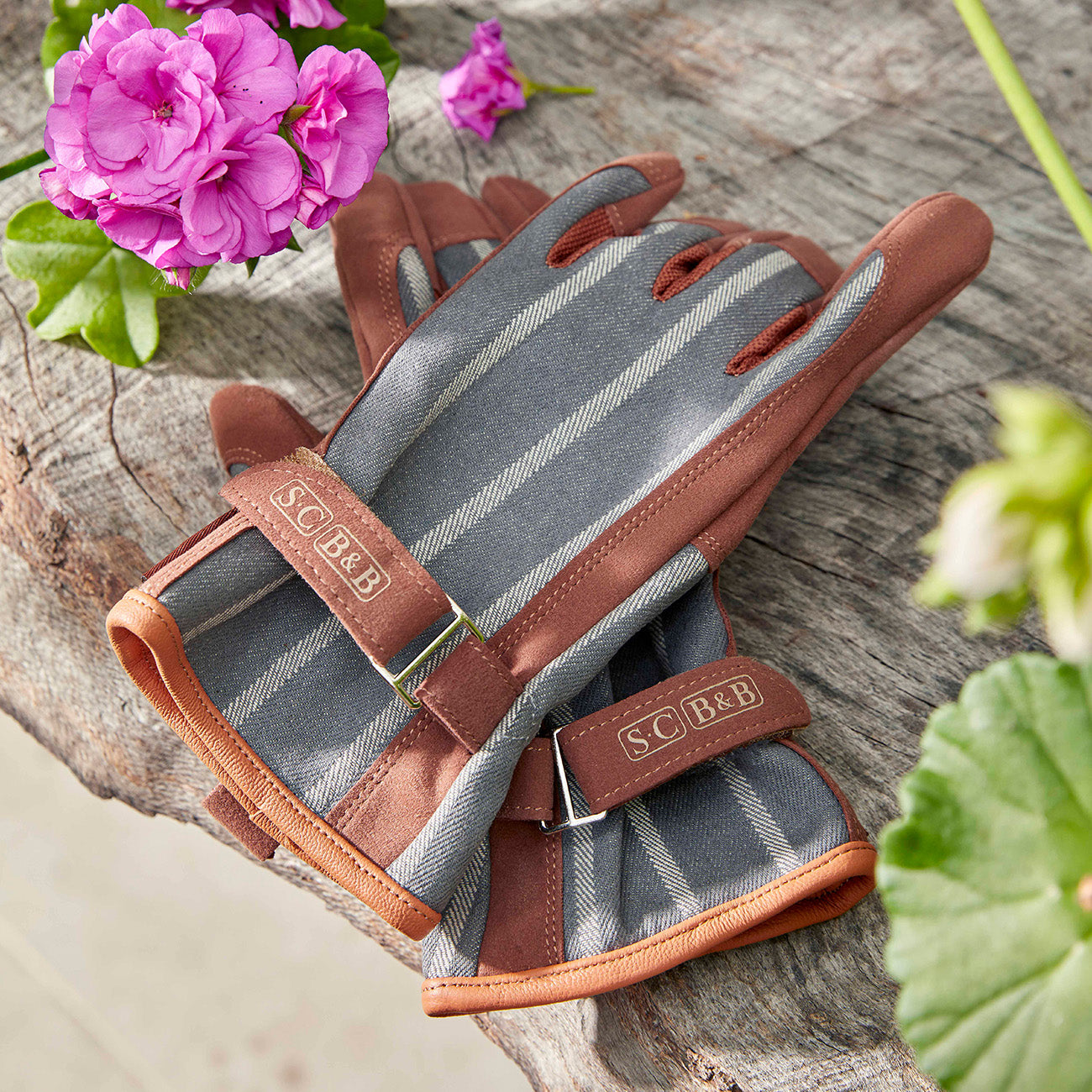 Sophie Conran for Burgon & Ball Everyday Gardening Gloves in grey ticking stripe placed on a garden bench.